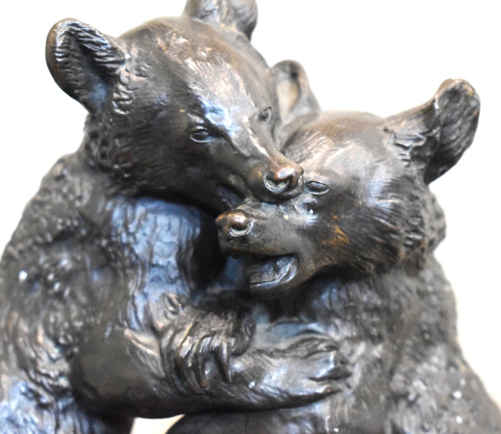 A dark patinated bronze sculpture depicting two play-fighting bear cubs standing on an integral naturalistic bronze base. View VI