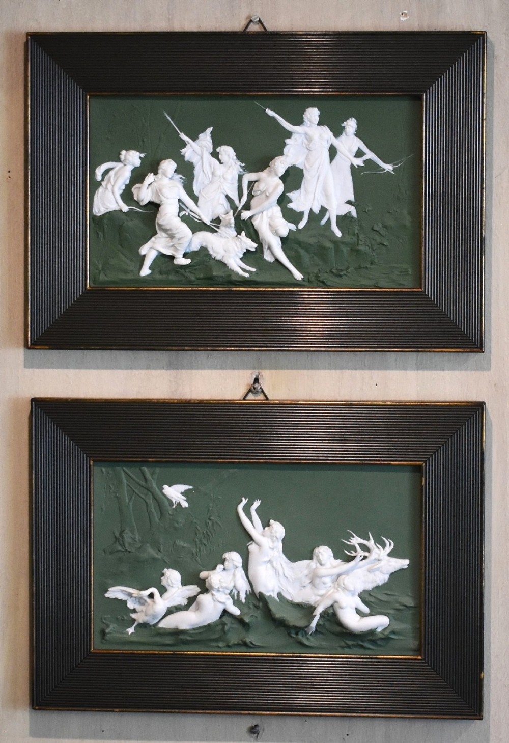 A pair of framed Art Nouveau Dresden porcelain plaques featuring white high-relief mythological figures on a dark green ground within reeded black frames. View II