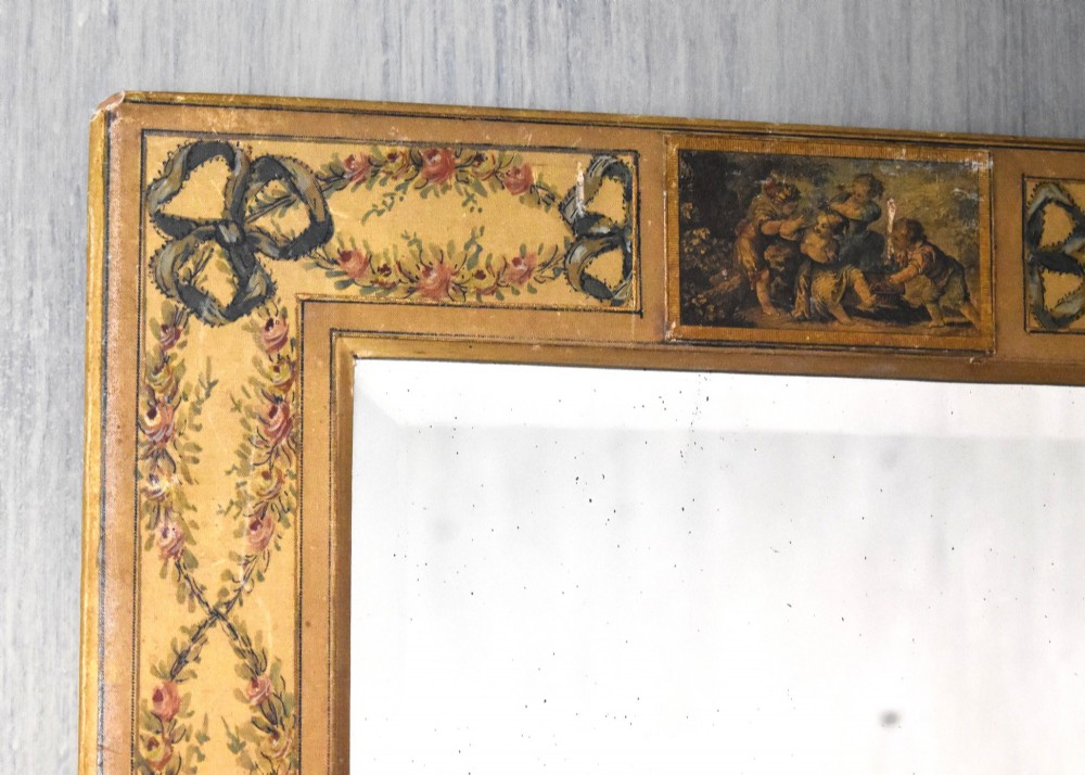 A rectangular wall mirror featuring a bevelled glass pane surrounded by a wide frame decorated with hand-painted silk motifs including ribbon bows, floral swags, and central medallions. View II