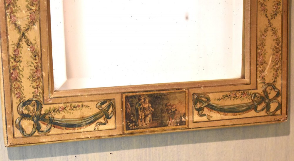 A rectangular wall mirror featuring a bevelled glass pane surrounded by a wide frame decorated with hand-painted silk motifs including ribbon bows, floral swags, and central medallions. View IV