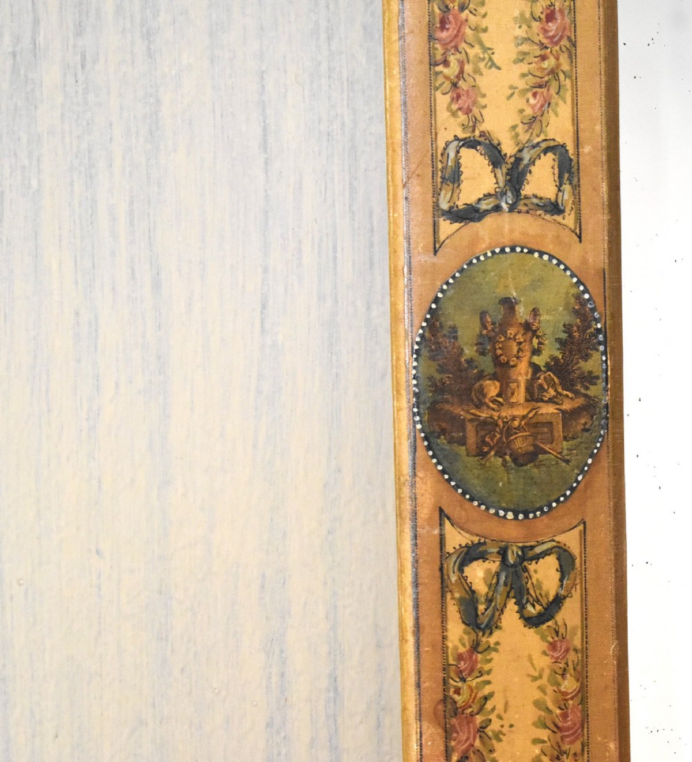 A rectangular wall mirror featuring a bevelled glass pane surrounded by a wide frame decorated with hand-painted silk motifs including ribbon bows, floral swags, and central medallions. View VI