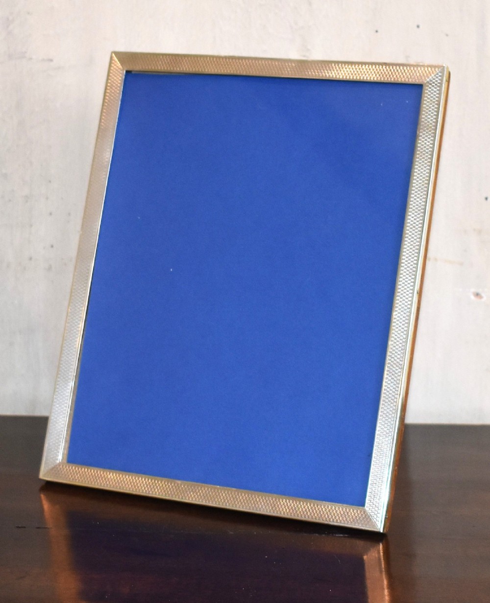 An upright rectangular Art Deco silver picture frame with textured engine-turned detailing around the border and a blue insert. View II
