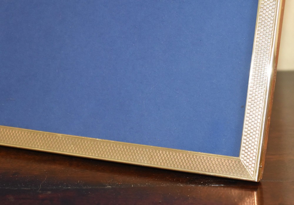 An upright rectangular Art Deco silver picture frame with textured engine-turned detailing around the border and a blue insert. View III