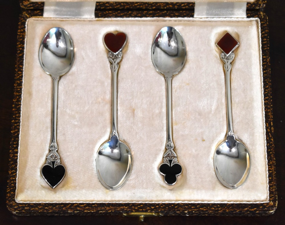A boxed set of four silver teaspoons featuring red and black enamel playing card suits on the terminals. View II