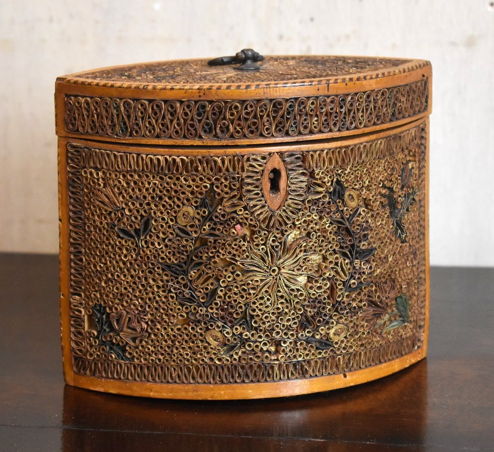 A late 18th-century Georgian navette-shaped tea caddy covered entirely in tight quilled paper scrolls with central floral panels.