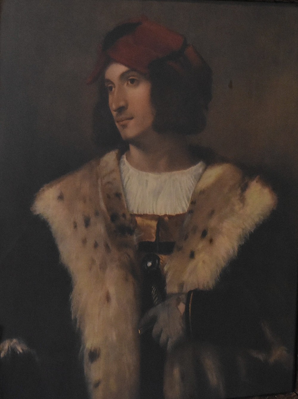A framed portrait print depicting a young man in a red cap and fur-trimmed coat after Titian, set inside a carved gilt frame. View IV