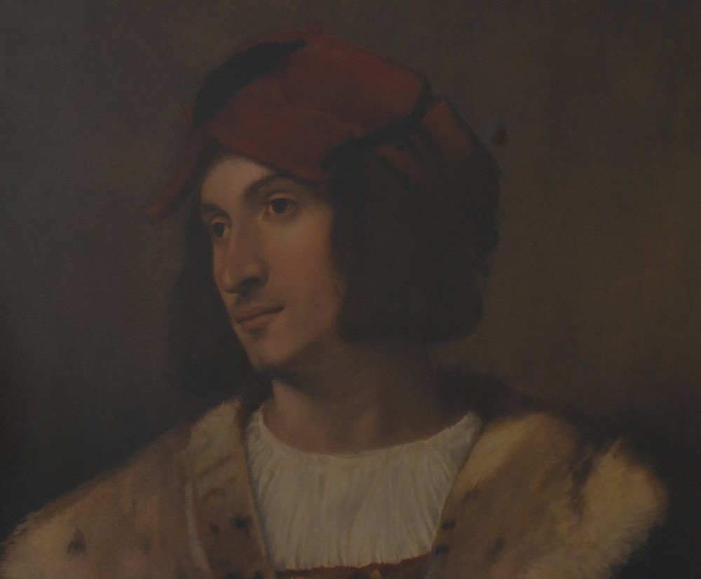 A framed portrait print depicting a young man in a red cap and fur-trimmed coat after Titian, set inside a carved gilt frame. View V