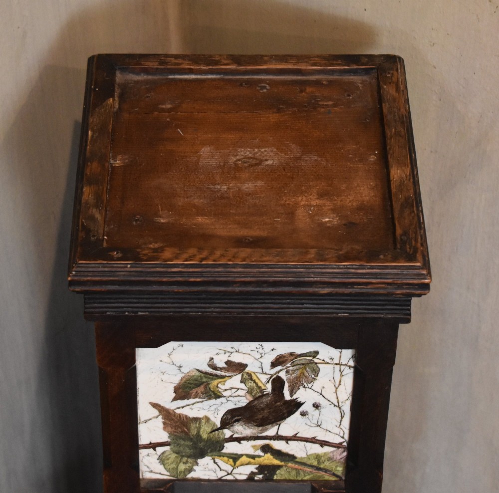 A dark wood Aesthetic Movement pedestal column with three vertical inset ceramic tiles displaying painted birds amidst foliage. View II