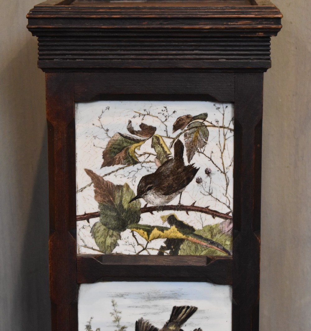 A dark wood Aesthetic Movement pedestal column with three vertical inset ceramic tiles displaying painted birds amidst foliage. View III