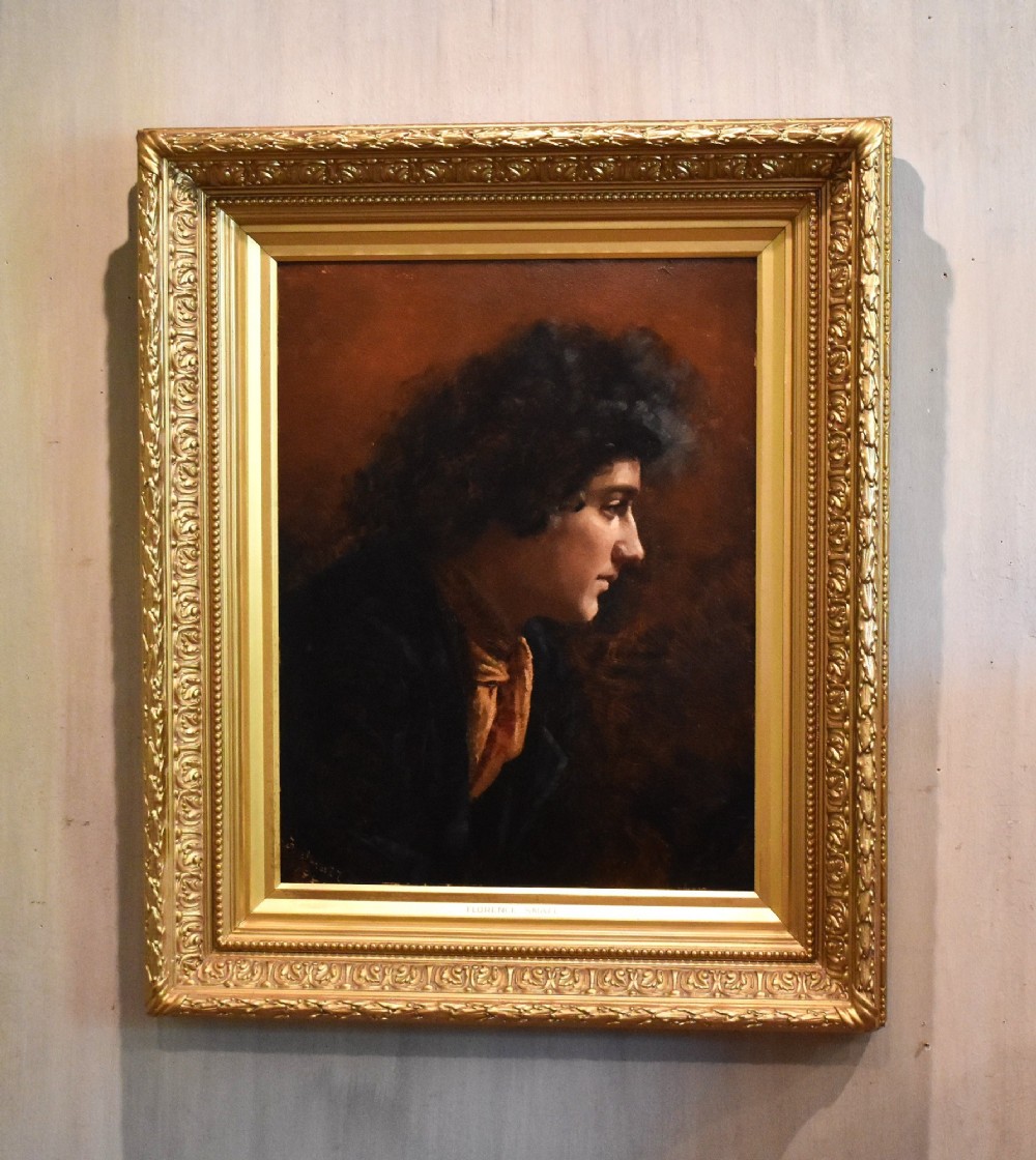 An antique Victorian profile oil painting depicting a figure with dark curly hair set within an ornate gilded frame.