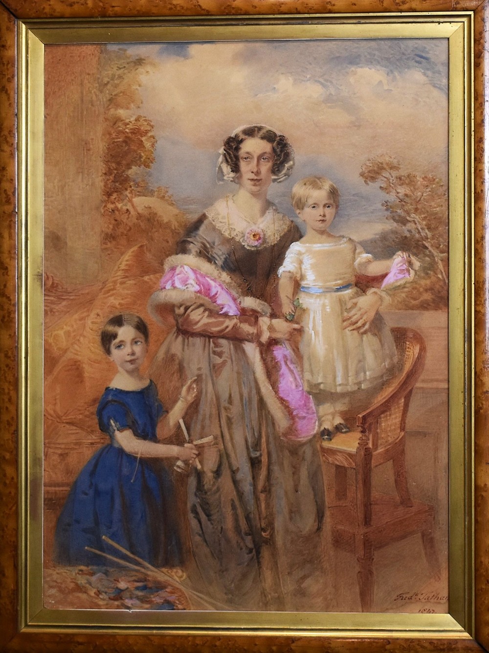 A mid-19th-century watercolour portrait depicting a mother with two young children, presented in a birds eye maple frame with a gold slip. View III