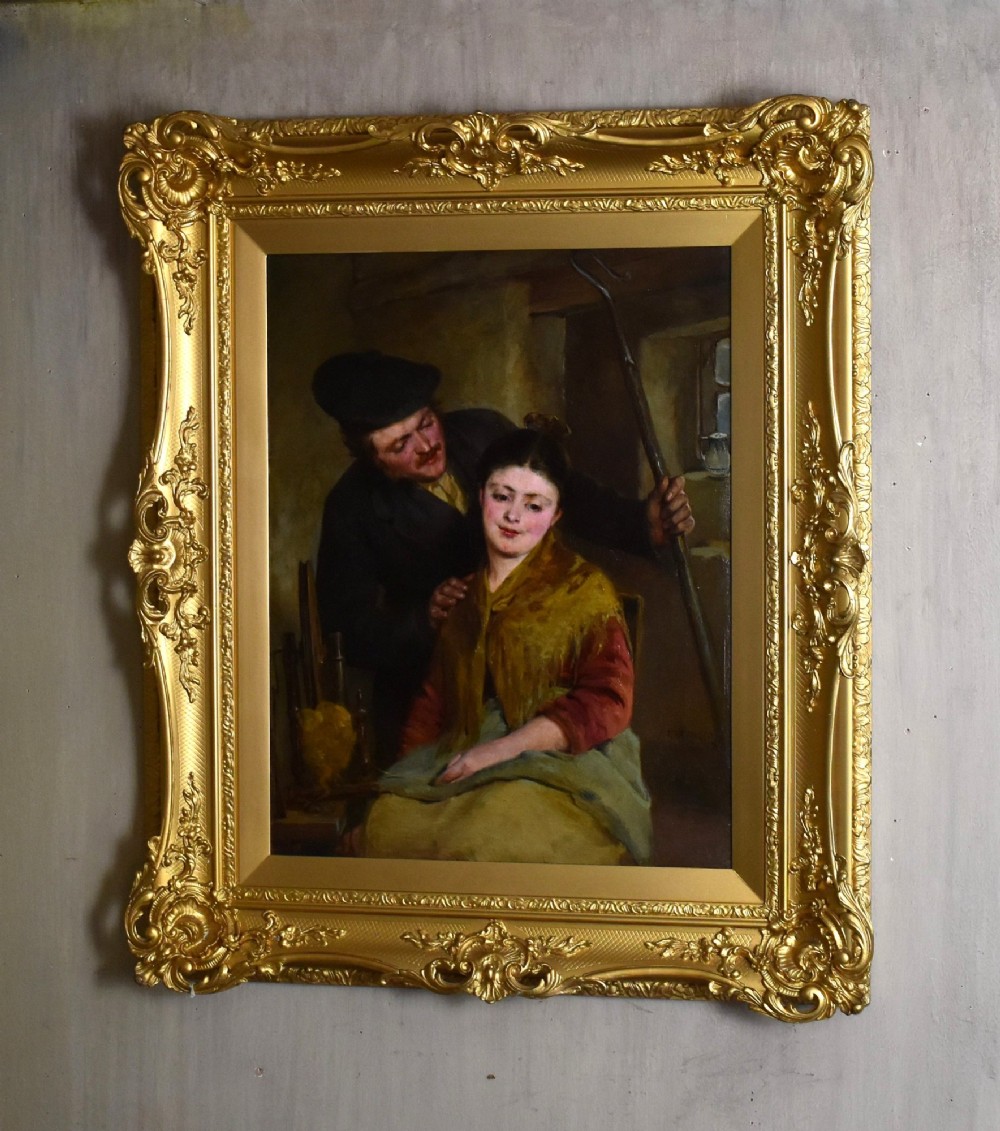A 19th-century genre oil painting in an ornate gilt frame depicting a seated woman wearing a yellow shawl with a standing man behind her inside a rustic interior.
