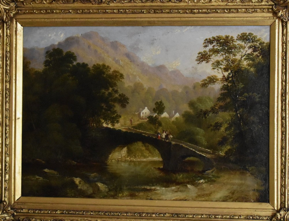 A nineteenth-century Victorian oil painting depicting a river scene with a stone arch bridge and distant mountains, housed within an ornate gilded frame. View III