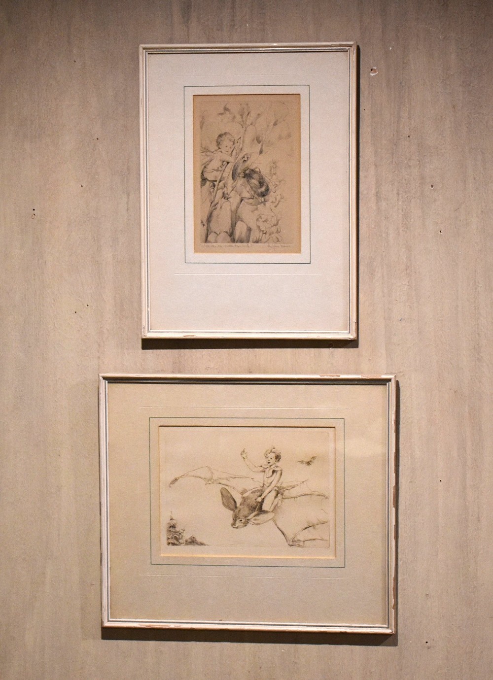 A pair of vertically stacked framed monochrome prints depicting illustrated scenes from Shakespeares The Tempest set within cream mounts and thin light frames.