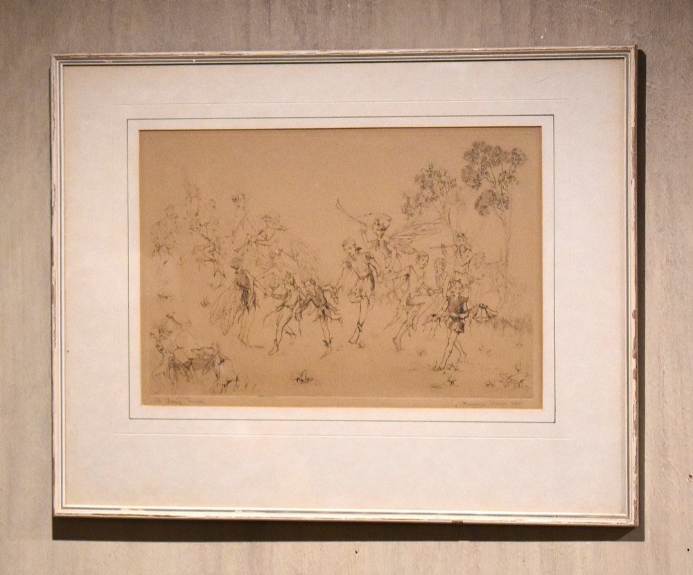 A framed sepia print depicting figures of fairies dancing and playing instruments in a grassy woodland, presented with a cream double mount and a thin painted frame.