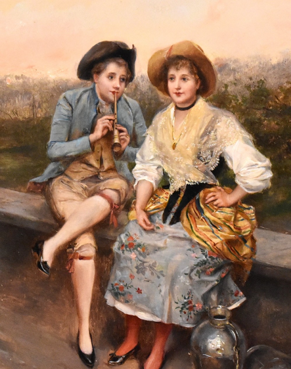 An oil painting depicting two figures in 18th-century costume seated outdoors, presented in a carved gilt wood frame. View V