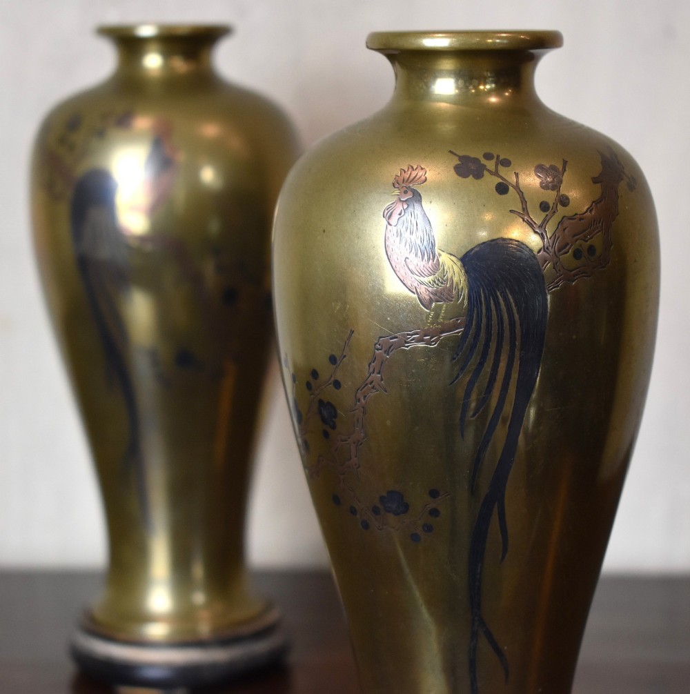 A pair of baluster-shaped golden bronze vases with detailed mixed-metal inlays depicting cockerels perched on branches, set on dark carved wooden bases. View IV