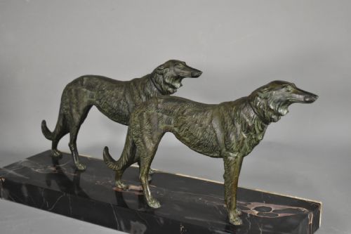 fig 1. An Art Deco patinated metal sculpture depicting two Borzoi dogs standing on a layered black marble and cream onyx plinth.