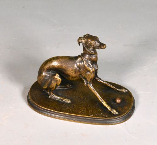 fig 1. A 19th-century patinated bronze sculpture depicting a greyhound crouched near a ball on an oval base.