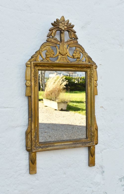 fig 1. A rectangular French giltwood wall mirror featuring carved floral cresting and a gold leaf frame.