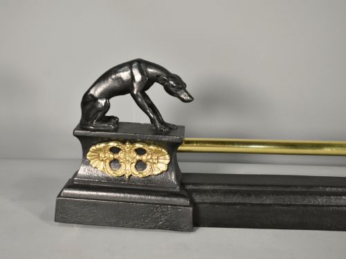 fig 1. A 19th-century French fireplace fender featuring dark patinated metal greyhound sculptures resting on bases on either side of a polished brass rail with central gold-toned foliate detailing.