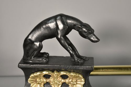 fig 2. A 19th-century French fireplace fender featuring dark patinated metal greyhound sculptures resting on bases on either side of a polished brass rail with central gold-toned foliate detailing.