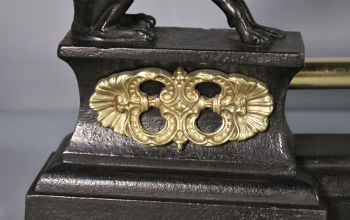 fig 3. A 19th-century French fireplace fender featuring dark patinated metal greyhound sculptures resting on bases on either side of a polished brass rail with central gold-toned foliate detailing.