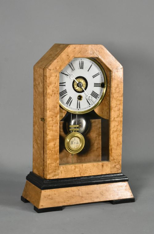 fig 1. An antique mantel clock featuring a birdseye maple veneered arched case, ebonised plinth base, white enamel dial with Roman numerals, and a brass pendulum.