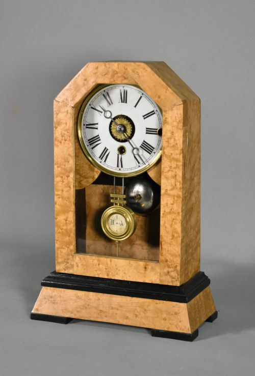 fig 2. An antique mantel clock featuring a birdseye maple veneered arched case, ebonised plinth base, white enamel dial with Roman numerals, and a brass pendulum.