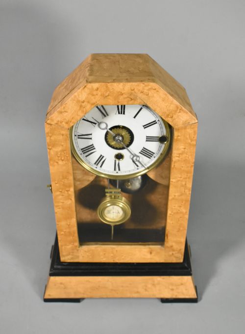fig 3. An antique mantel clock featuring a birdseye maple veneered arched case, ebonised plinth base, white enamel dial with Roman numerals, and a brass pendulum.