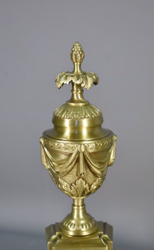 fig 1. A pair of nineteenth-century French bronze fire dogs featuring carved urn finials, draped swags, and openwork bases.