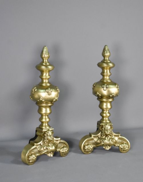 fig 1. A pair of cast bronze Louis XIV style firedogs featuring baluster shafts, flame finials, and scrolled bases with relief mask carvings.