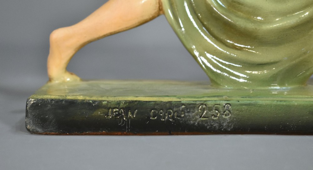 An Art Deco painted plaster figurine depicting a female dancer holding a draped green dress on a dark rectangular base. View VII