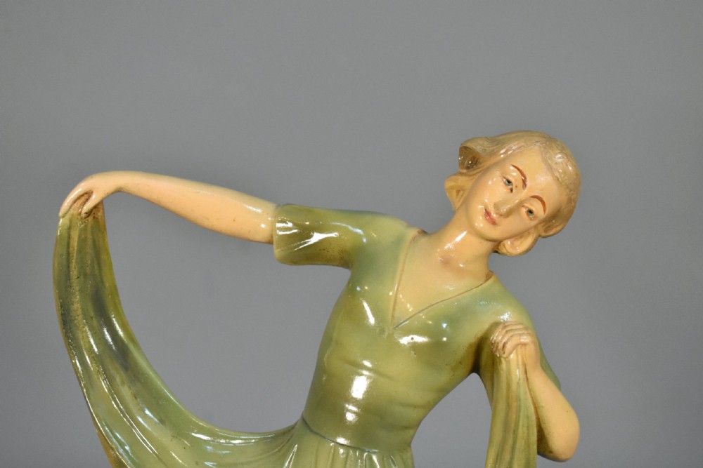 An Art Deco painted plaster figurine depicting a female dancer holding a draped green dress on a dark rectangular base. View XIII