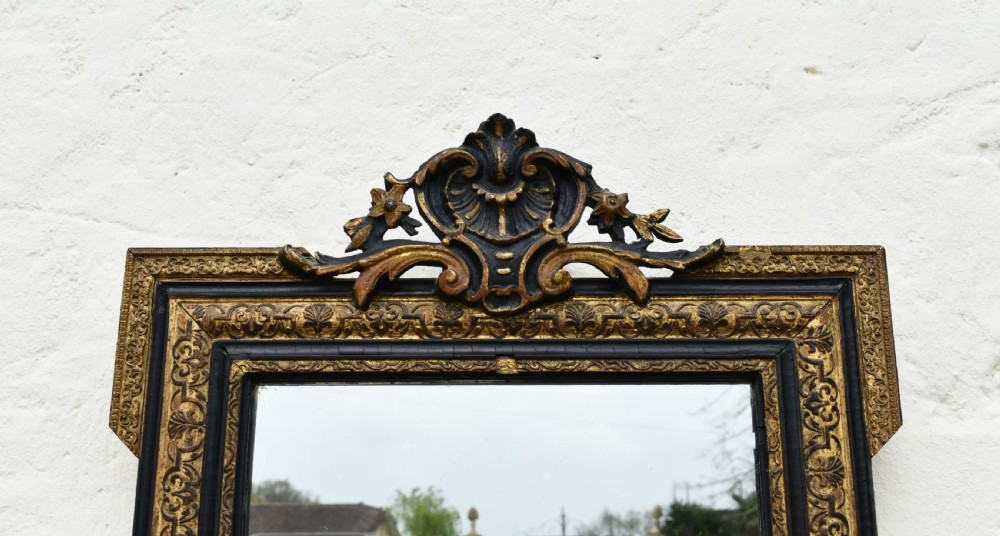 A rectangular Napoleon III wall mirror featuring a carved giltwood frame with black ebonised inner border and ornamental cresting. View IV