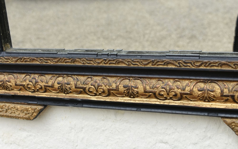 A rectangular Napoleon III wall mirror featuring a carved giltwood frame with black ebonised inner border and ornamental cresting. View XV