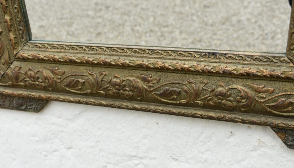 A rectangular antique French Napoleon III giltwood wall mirror with an ornate carved floral frame and top acanthus crest. View XIV