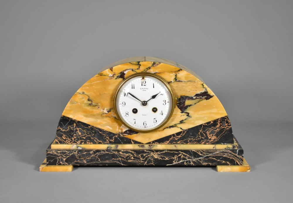 A French Art Deco mantel clock set featuring an arched yellow and black veined marble clock flanked by two matching marble chalice garnitures. View II