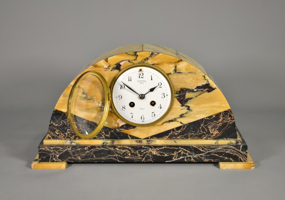 A French Art Deco mantel clock set featuring an arched yellow and black veined marble clock flanked by two matching marble chalice garnitures. View VI