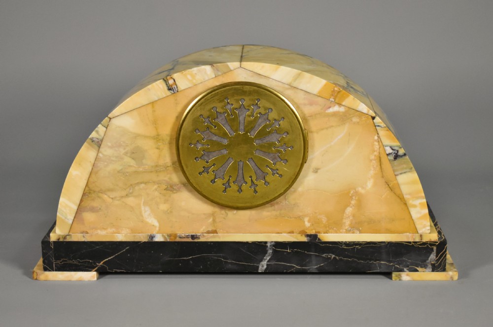 A French Art Deco mantel clock set featuring an arched yellow and black veined marble clock flanked by two matching marble chalice garnitures. View VIII
