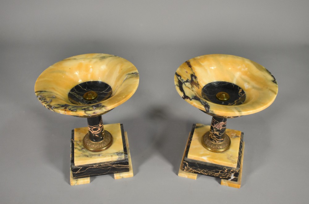 A French Art Deco mantel clock set featuring an arched yellow and black veined marble clock flanked by two matching marble chalice garnitures. View XV