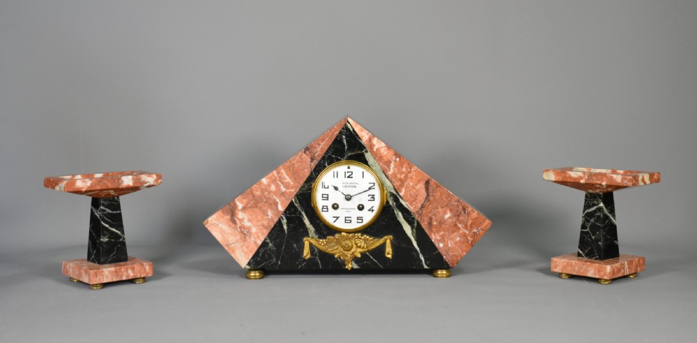 A French Art Deco three-piece clock set made from geometric pink and black veined marble with brass mounts.