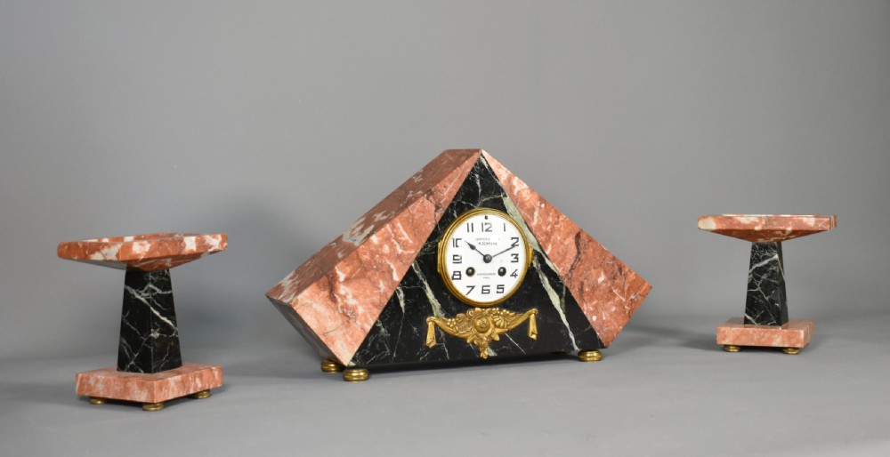 A French Art Deco three-piece clock set made from geometric pink and black veined marble with brass mounts. View II