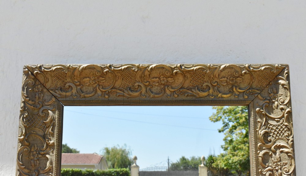 A 19th-century rectangular French giltwood wall mirror featuring ornate carved foliate scrolls, lattice diaperwork motifs, and an aged gold finish. View VI