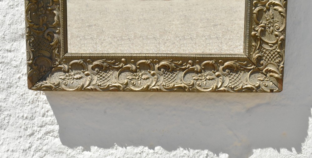 A 19th-century rectangular French giltwood wall mirror featuring ornate carved foliate scrolls, lattice diaperwork motifs, and an aged gold finish. View X