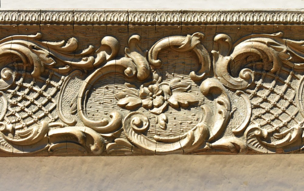 A 19th-century rectangular French giltwood wall mirror featuring ornate carved foliate scrolls, lattice diaperwork motifs, and an aged gold finish. View XI