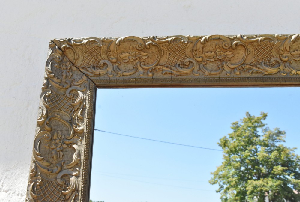 A 19th-century rectangular French giltwood wall mirror featuring ornate carved foliate scrolls, lattice diaperwork motifs, and an aged gold finish. View XV