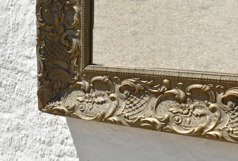 A 19th-century rectangular French giltwood wall mirror featuring ornate carved foliate scrolls, lattice diaperwork motifs, and an aged gold finish. View XVII