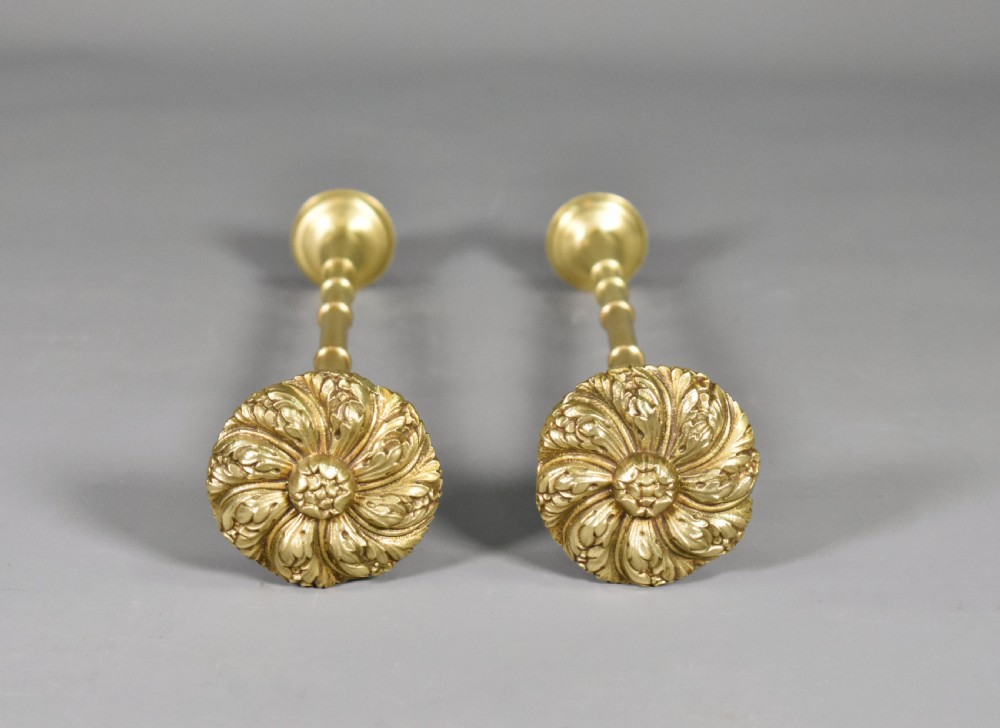 A pair of Second Empire French brass curtain tie-backs featuring circular carved floral rosettes on extended stems.