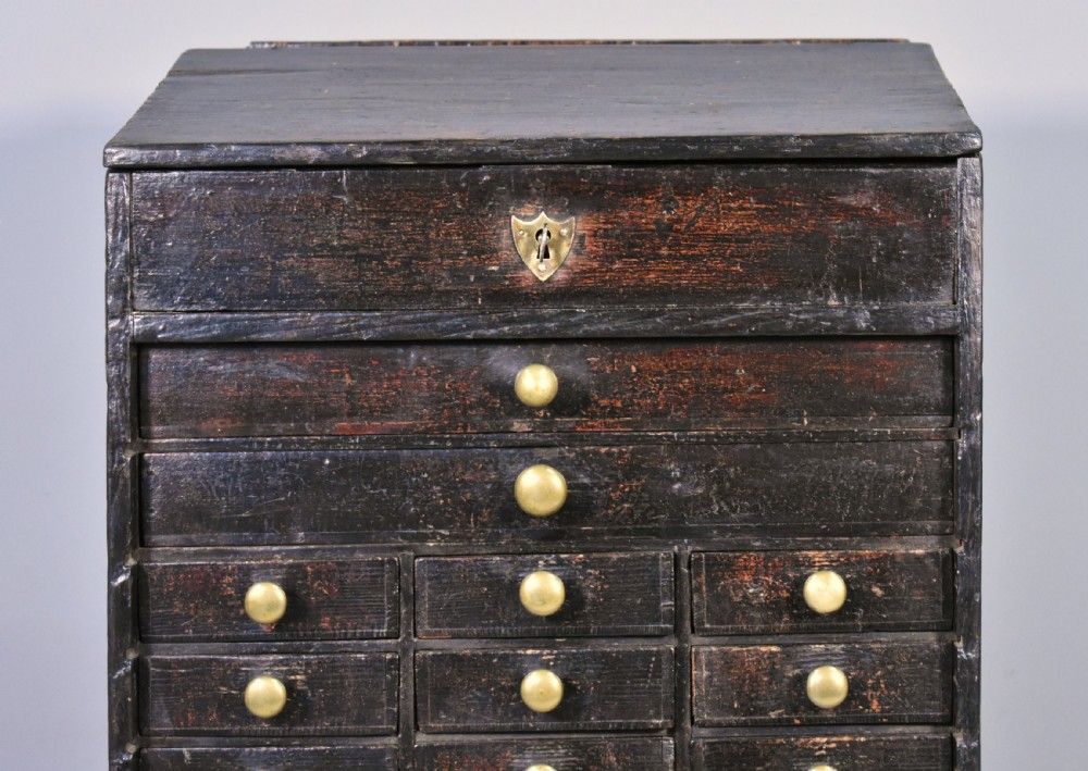 A tall dark wood antique horologist cabinet featuring multiple small drawers with brass knobs and a top compartment with a keyhole escutcheon. View VIII